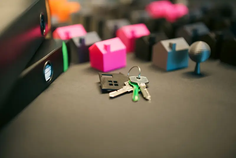 House keys on a desk beside rows of small model houses