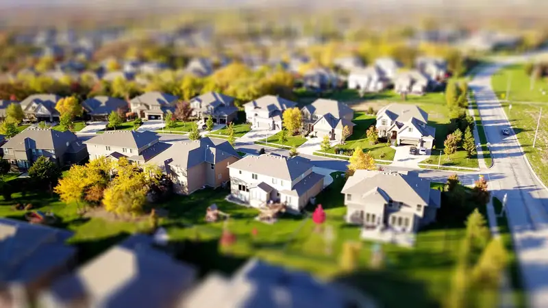 High-angle view of a suburban neighborhood with lawns, driveways and curving streets